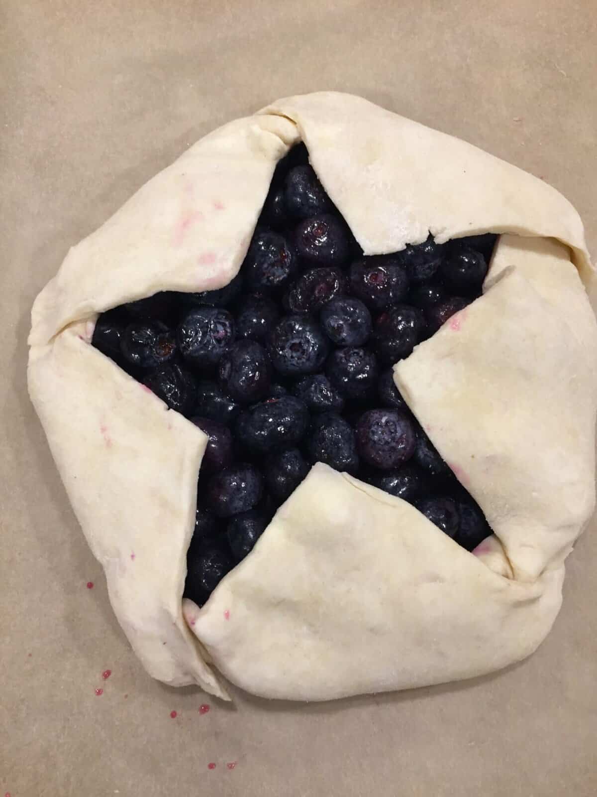 an unbaked blueberry galette with a star-shaped opening