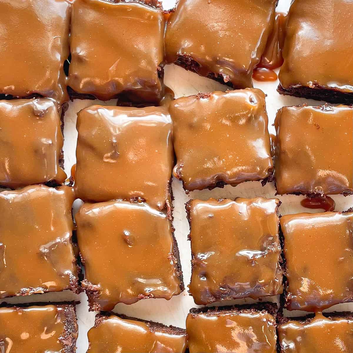 16 cut espresso brownies topped with gooey caramel on a white background.