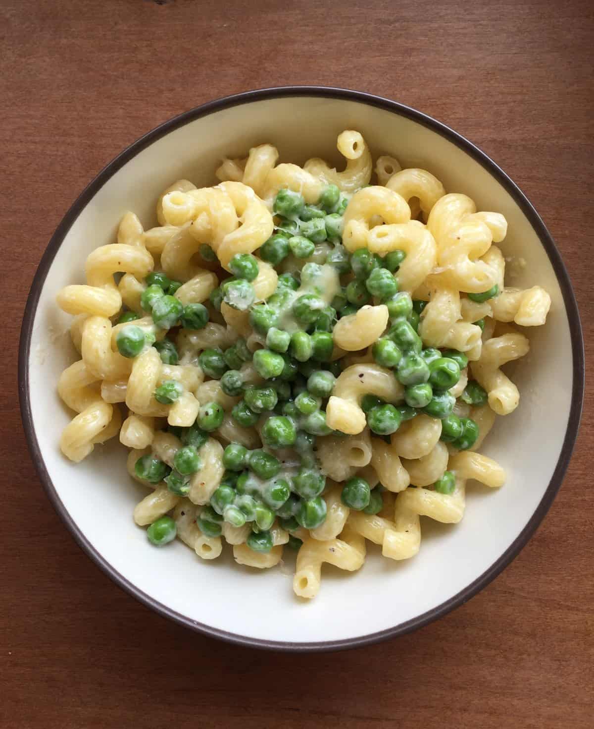 a bowl of cavatappi alfredo with peas