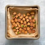 pan of baked tofu in parchment garnished with green onions.