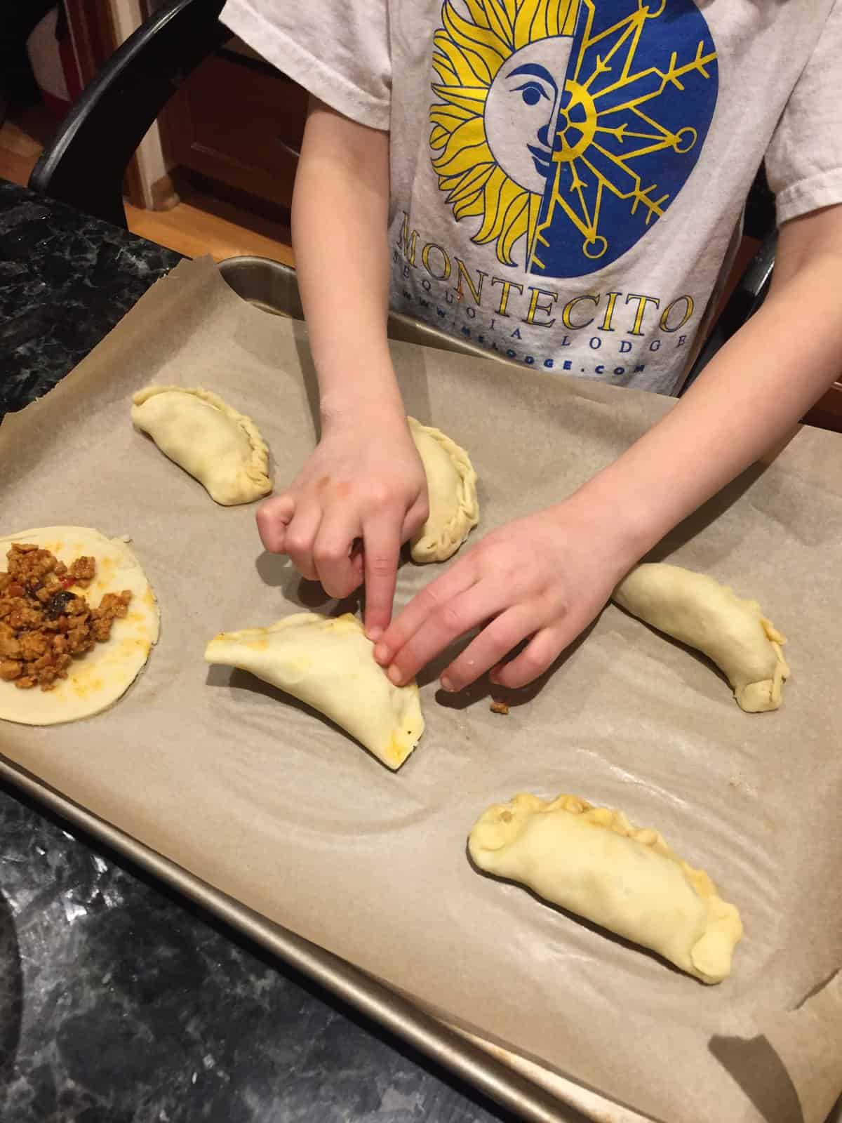 sealing the folded chicken empanadas.