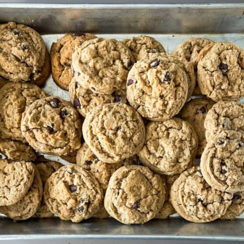 peanut butter chocolate chip cookies stacked on each other in a baking pan.