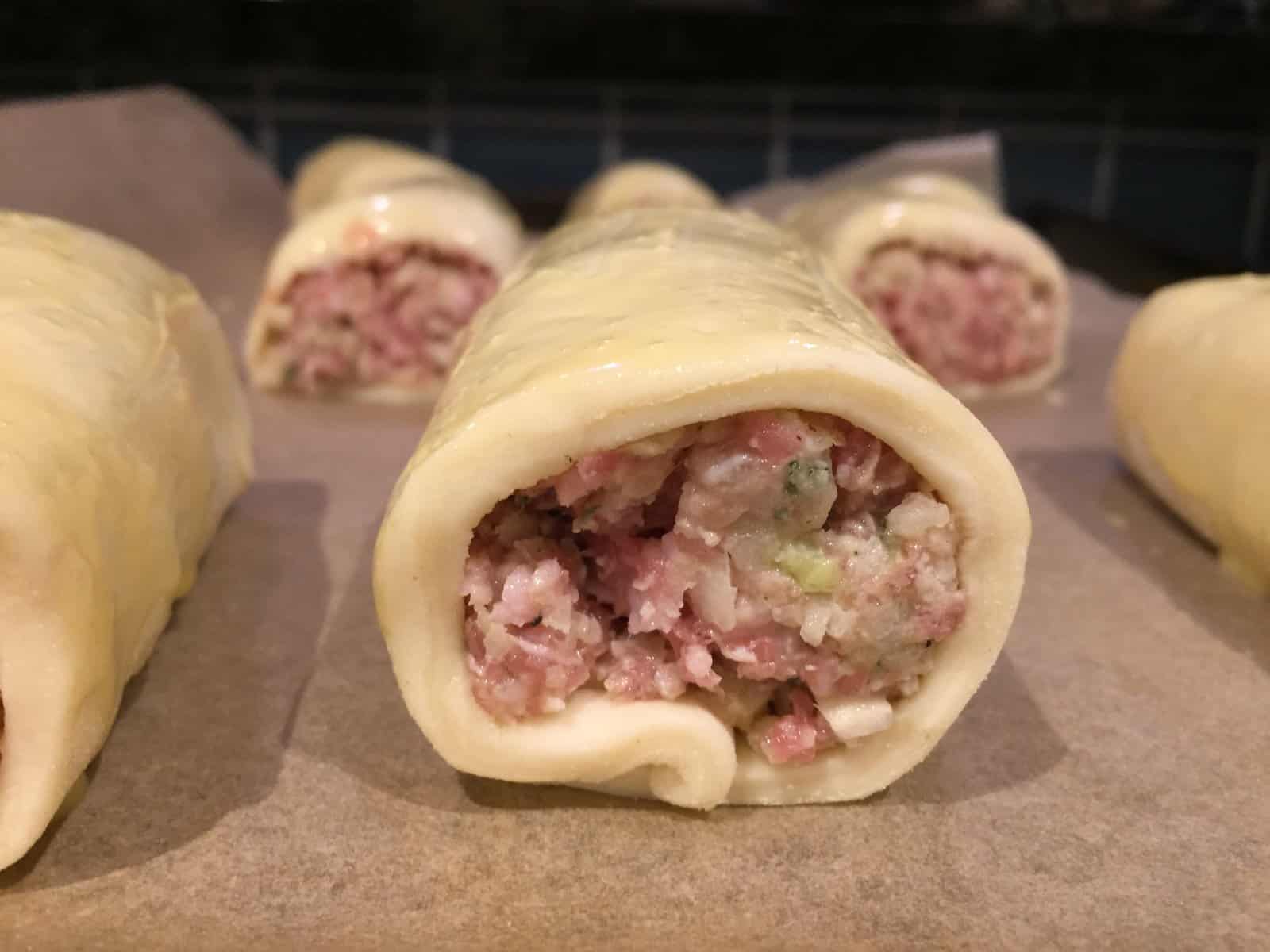 unbaked sausage rolls wrapped in puff pastry.