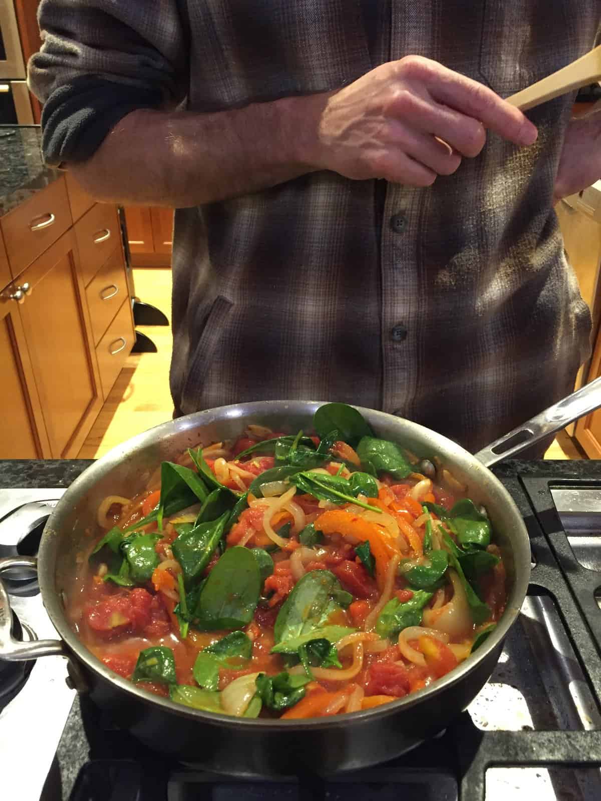 A pan with peppers, onions, tomatoes, and greens.