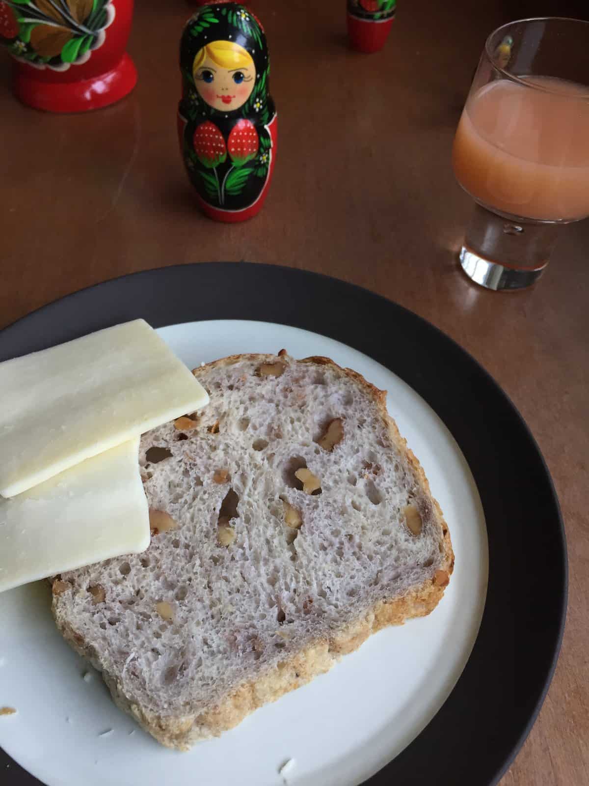 slice of sourdough discard bread with walnuts on a plate with cheese slices.