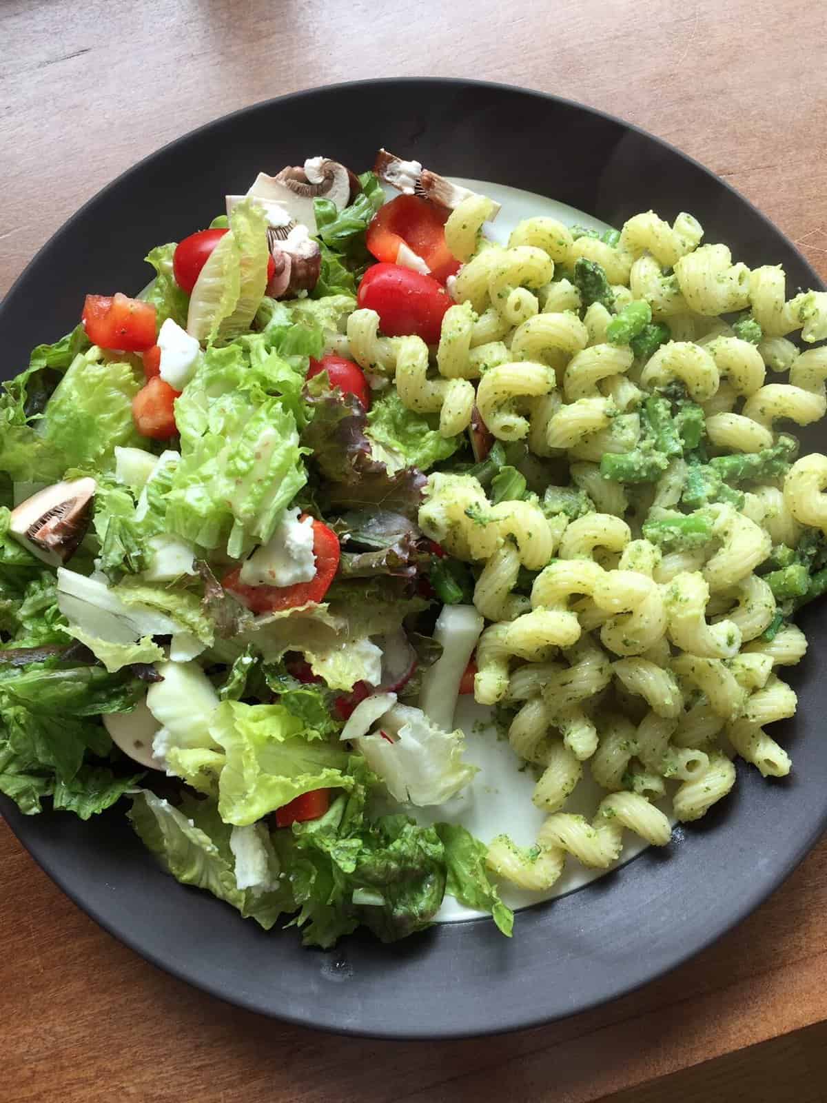 a plate of cavatappi with broccoli pesto and a side salad.