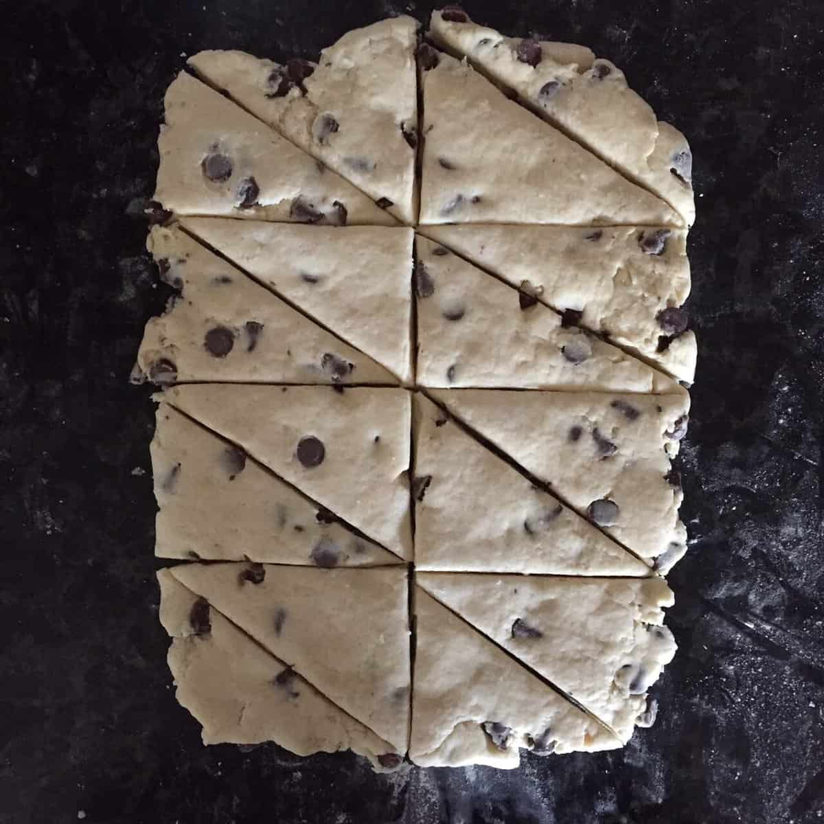 rolled out chocolate chip scone dough cut into sixteen right angled triangles .