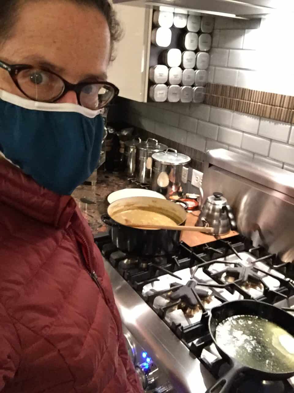 Joanne from the ugly duckling bakery blog browning butter in a cast iron skilled while wearing a mask.