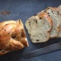 a 5 braid raisin challah with four slices and bread knife.