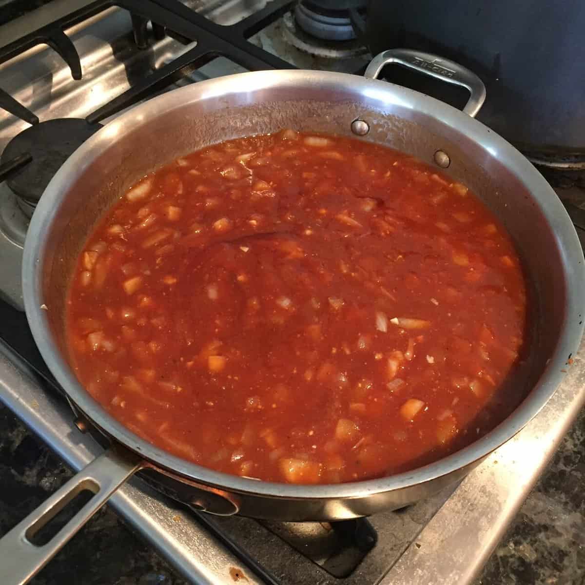 pan of homemade barbecue sauce with bits of chopped onions.