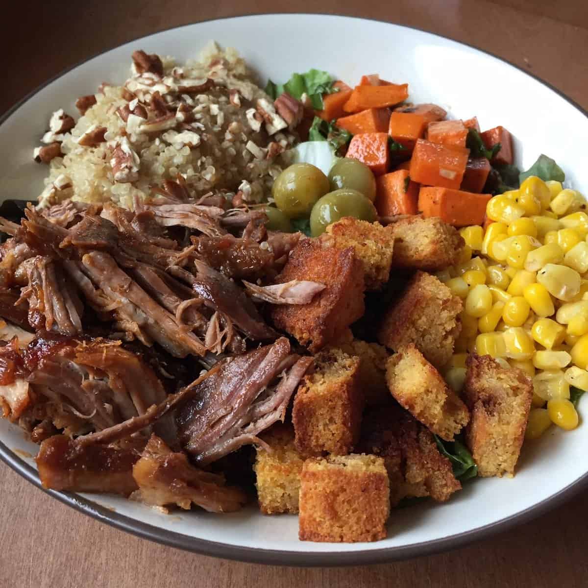 pulled pork bowl with cornbread croutons, corn, sweet potatoes, and quinoa.