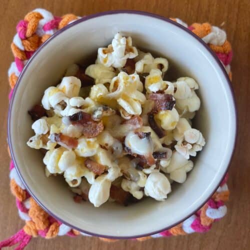 a small bowl of bacon cheddar popcorn on a colorful potholder.