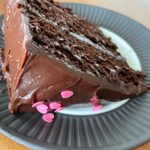 a slice of triple layer chocolate cake with chocolate ganache.