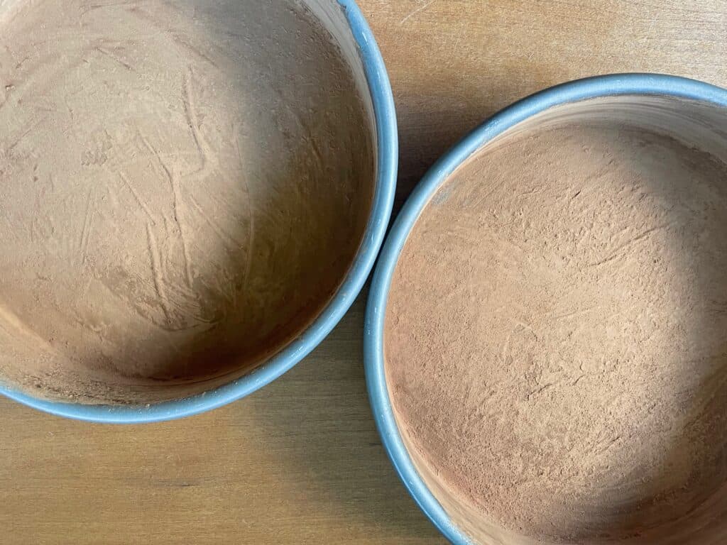 two cake pans floured with cocoa.