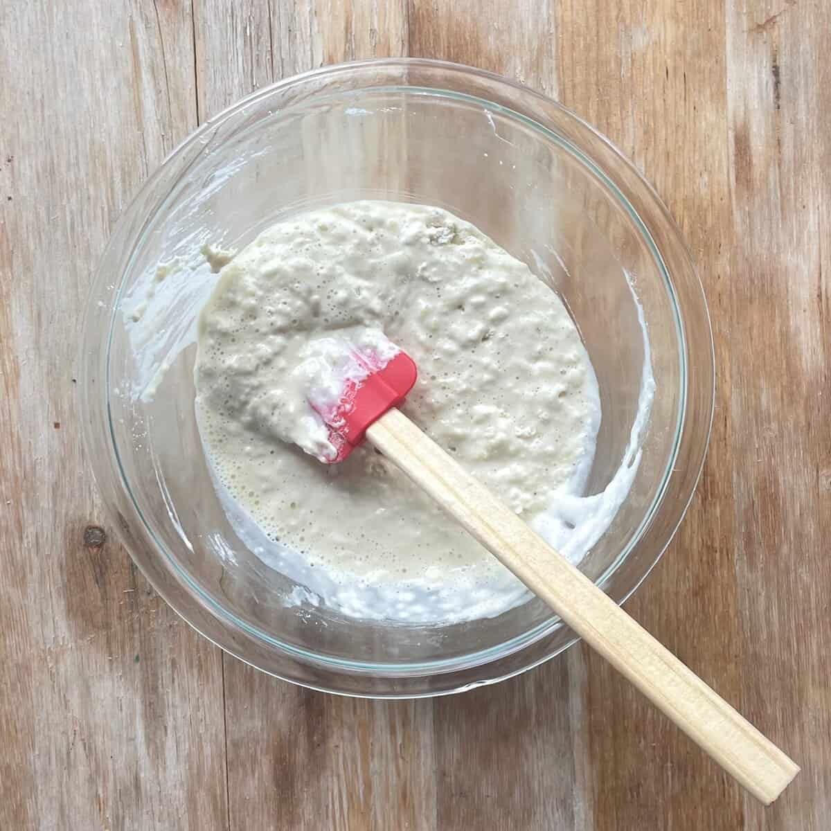 muffin batter in a glass bowl with a silicone spatula.