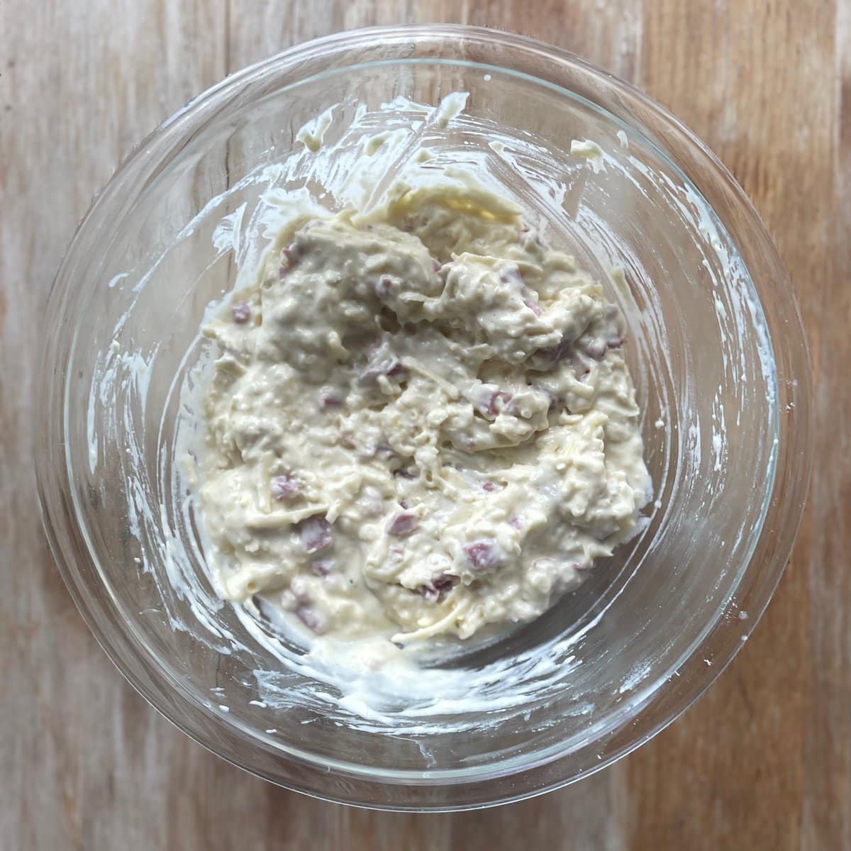 waffle batter with chopped ham and shredded cheese in a glass bowl.