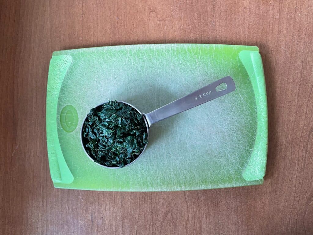 a measuring cup filled with the now cooked kale.