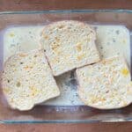 three slices of bread soaking up the orange zest French toast mixture.