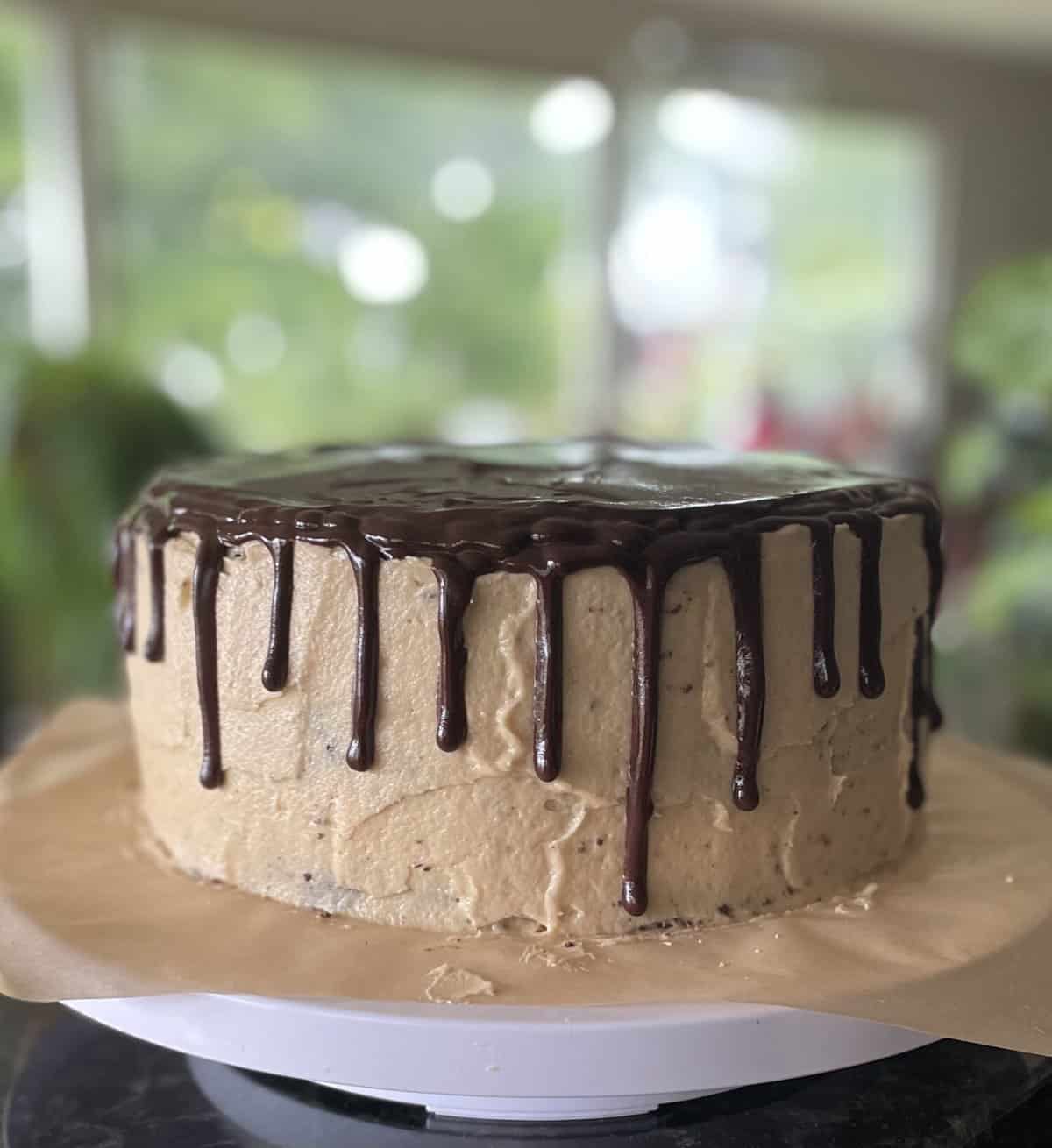 a peanut butter chocolate ganache drip cake on a cake stand