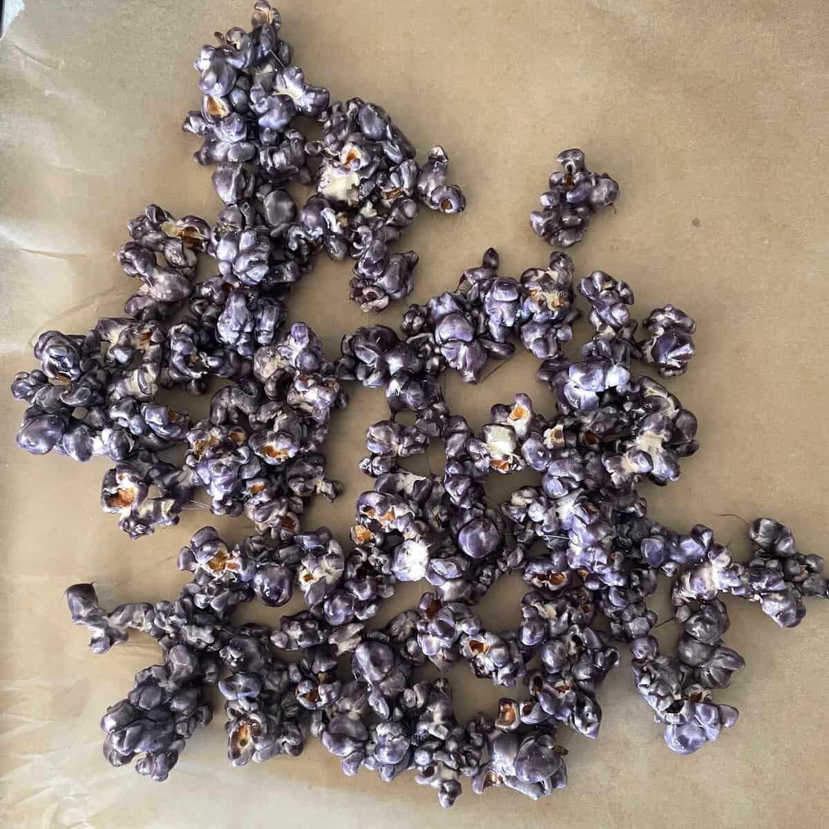 clusters of purple caramel popcorn on parchment paper.