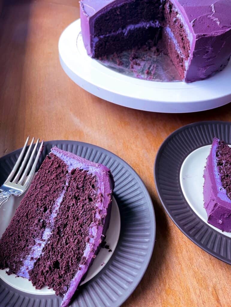 two slices of purple velvet cake and a cake stand.