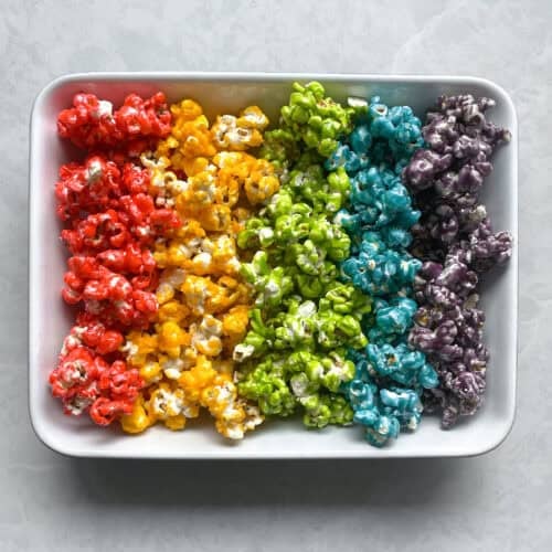lines of rainbow popcorn in rainbow order in a rectangular dish.