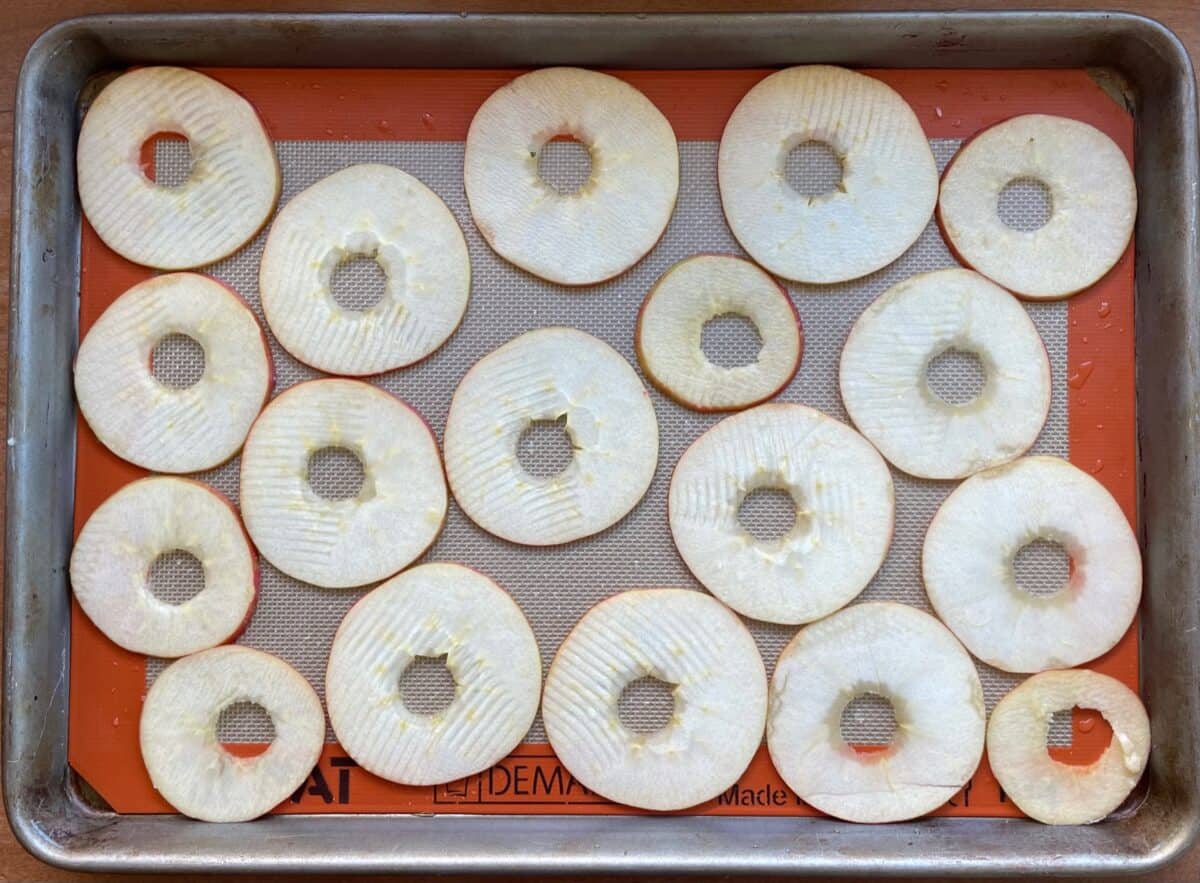 apple rings on a baking sheet lined with silicone mat.