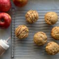 sourdough apple muffins on a cooling rack with glaze and fresh apples.