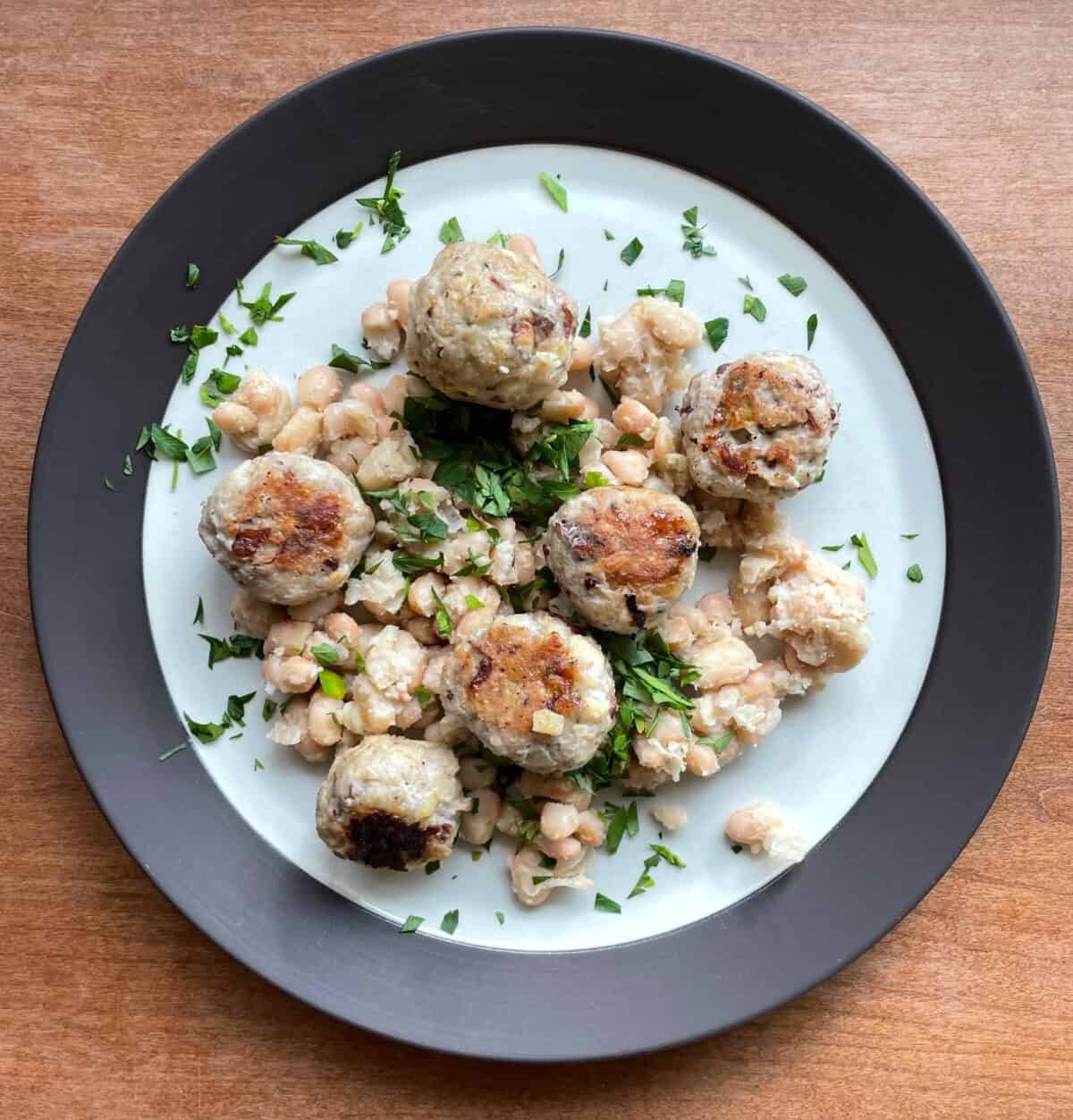 a plate of chicken and apple meatballs with white beans and parsley.