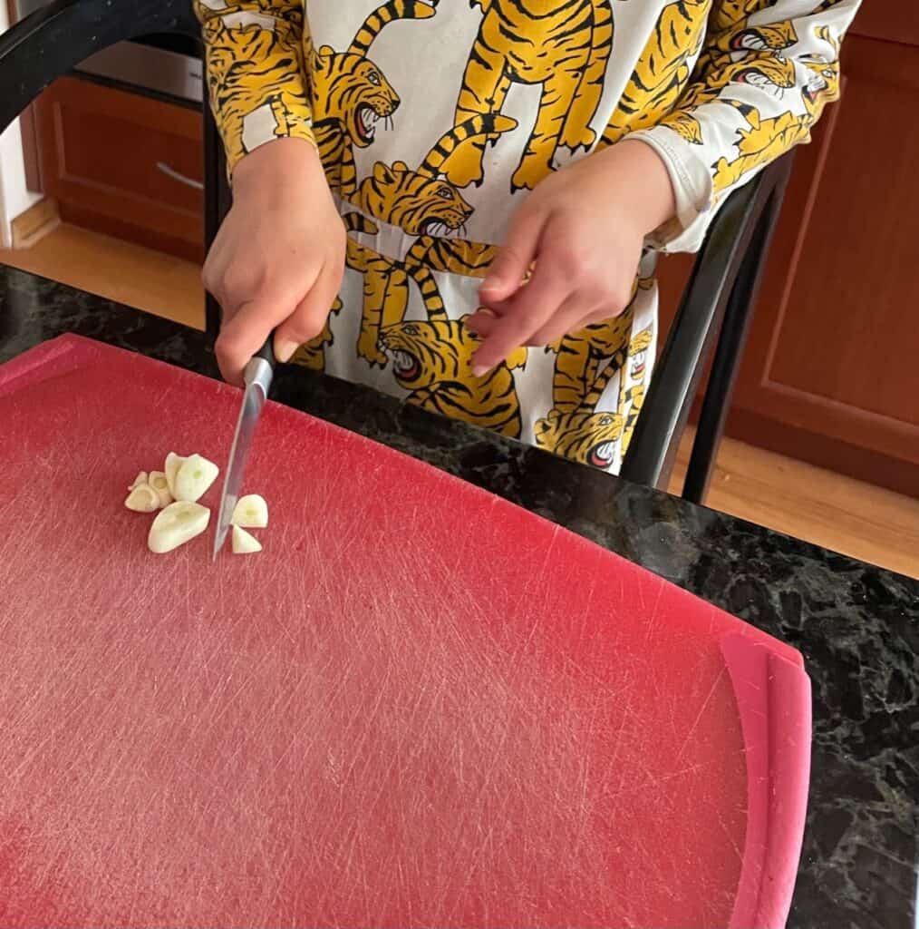 kiddo chopping peeled garlic.