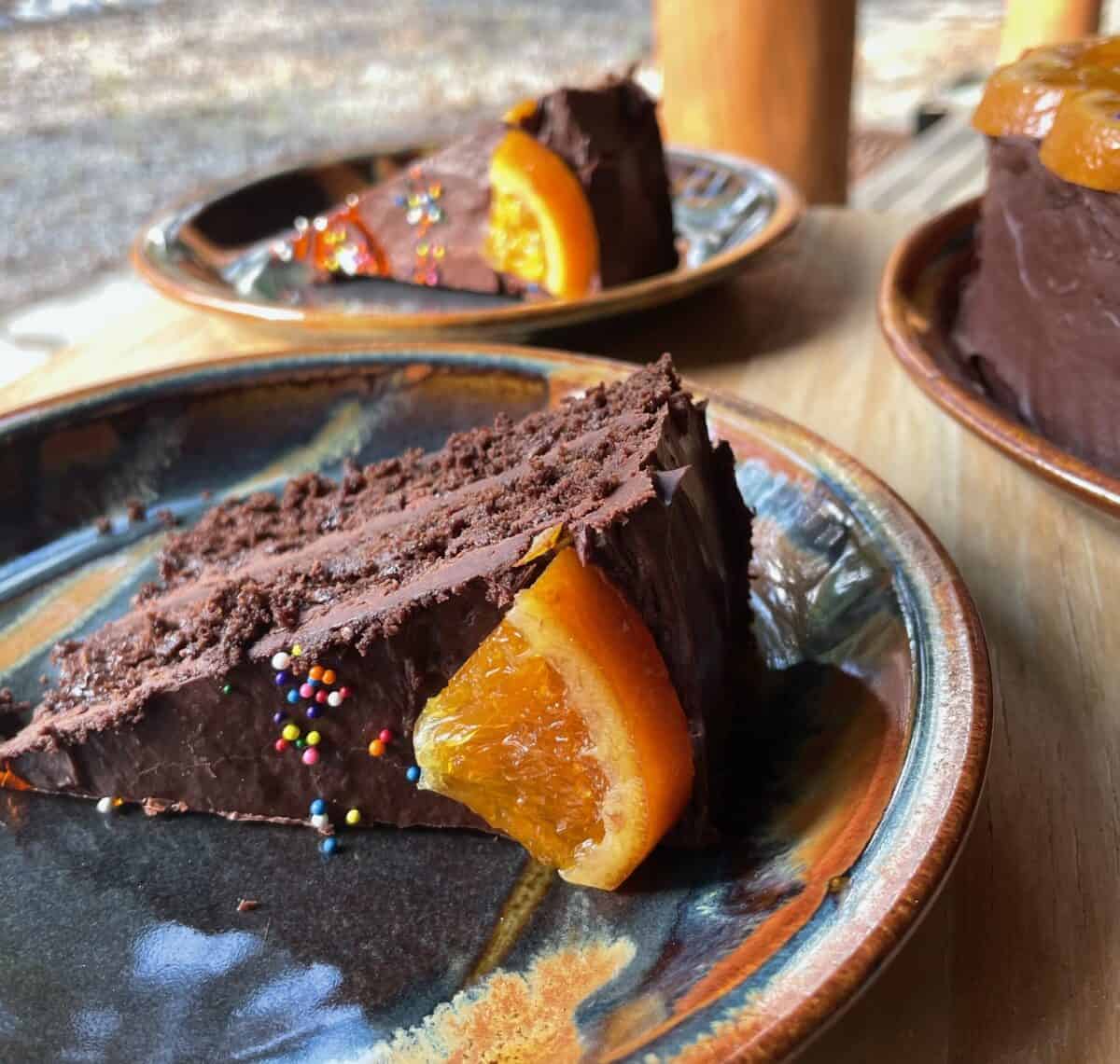 Two slices of chocolate orange cake with a candied orange wedge.