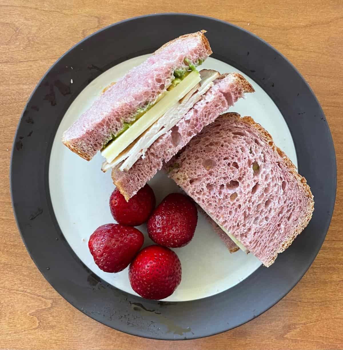 a plate with a turkey sandwich made with a pink colored bread.