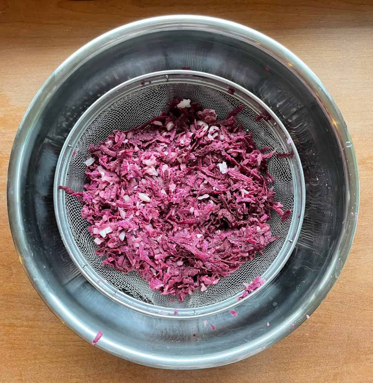 a bowl of grated purple sweet potatoes and onions