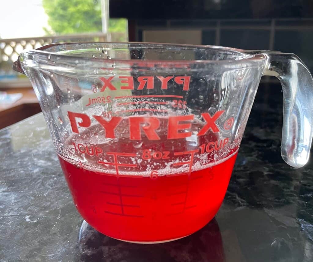 strawberry simple syrup in a measuring cup.