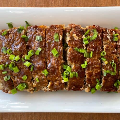 platter with sliced ground duck meatloaf garnished with chopped green onions.
