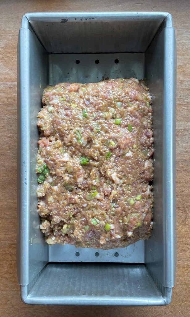 uncooked ground duck meatloaf packed into a meatloaf pan.