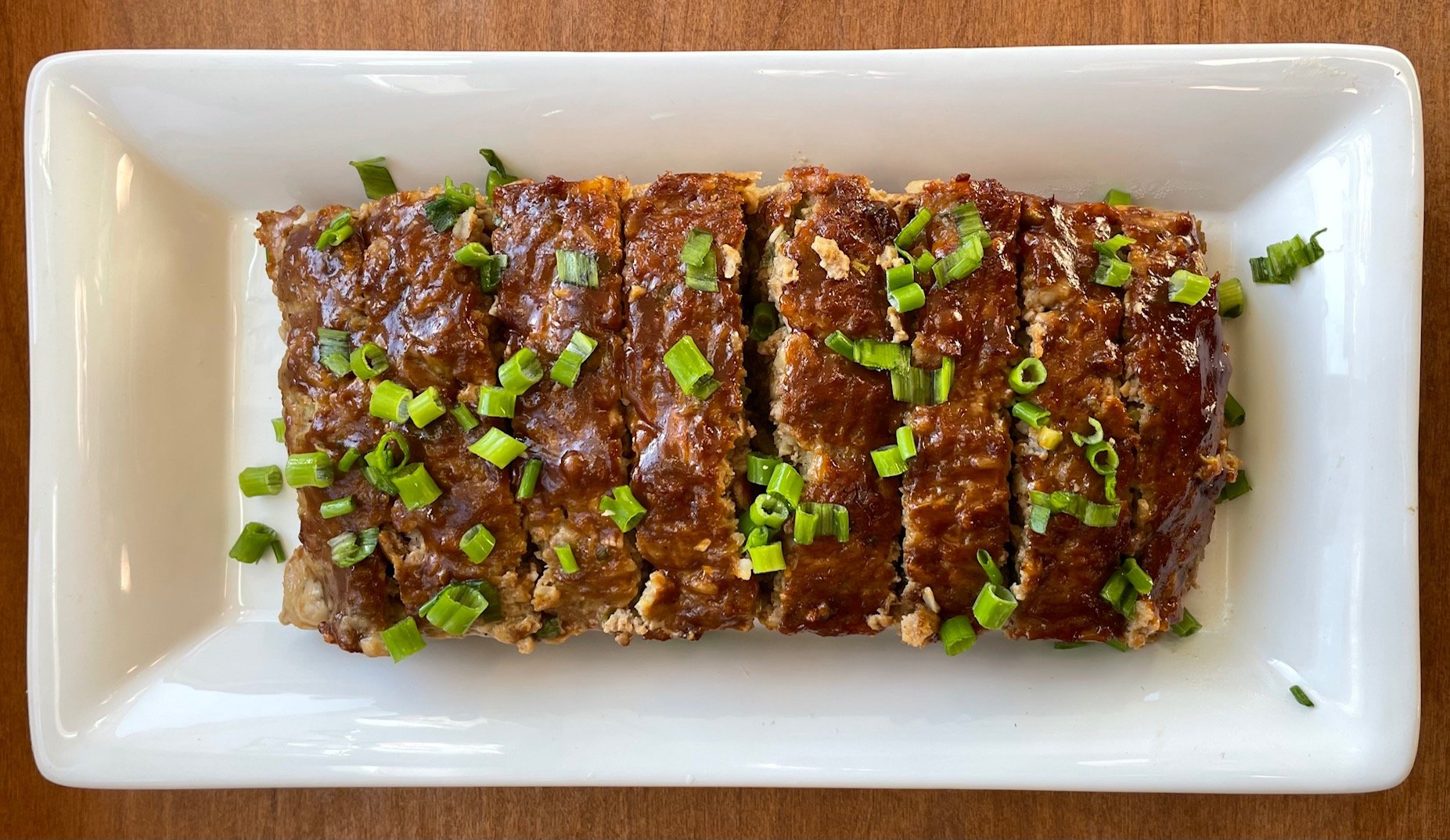 a platter of sliced meatloaf garnished with sliced green onions