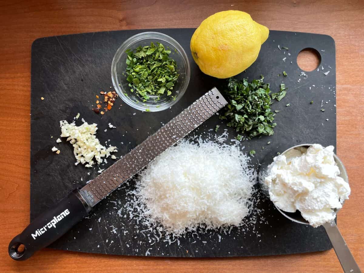 ricotta, lemon, Parmesan, garlic, herbs and spices on a cutting board.