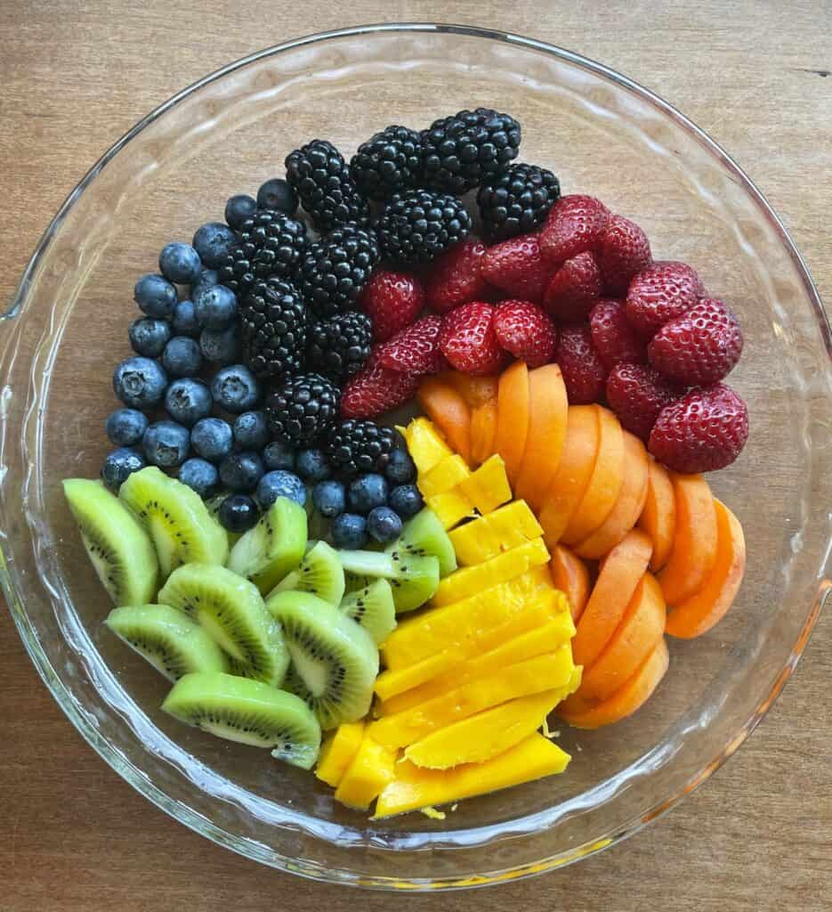 six colors of fruit laid out in a glass pie pan.