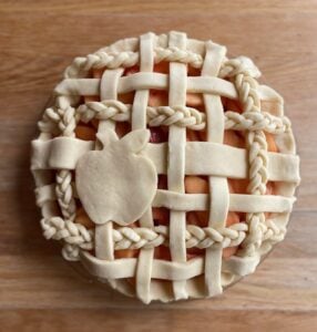 unbaked strawberry apple pie with a braided lattice top and apple cutout.