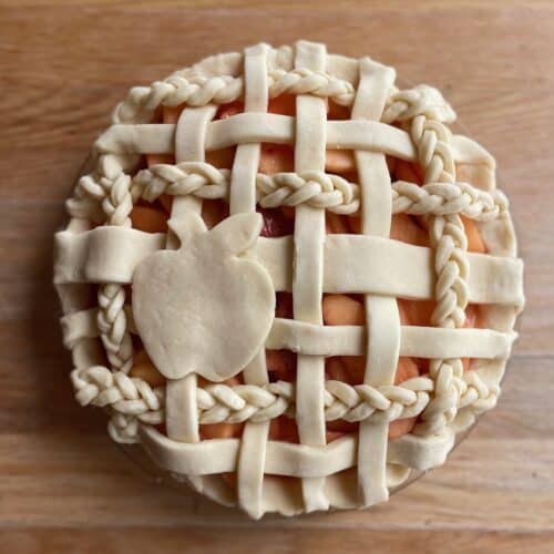 unbaked strawberry apple pie with a braided lattice top and apple cutout.