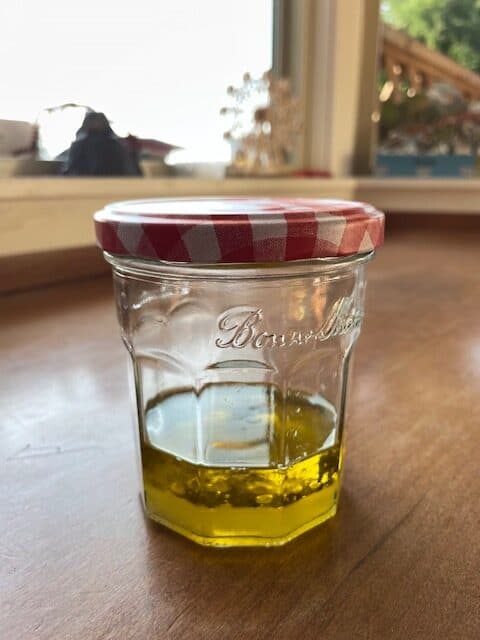 A jar filled with salad dressing that has partially separated.