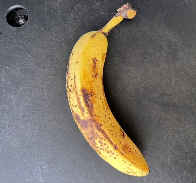 one very ripe banana on a cutting board.