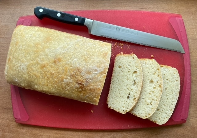 a loaf of sourdough bread, three slices, and a bread knife.