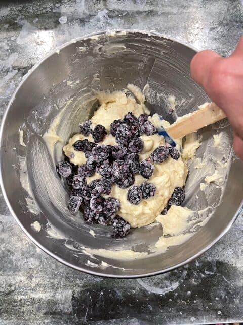 blackberries being stirred into the blackberry lemon loaf cake batter.