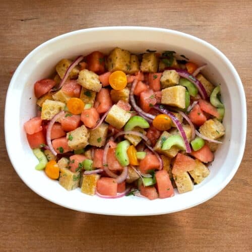 a serving bowl containing watermelon panzanella made with sourdough croutons