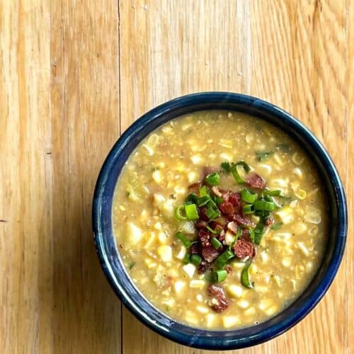a bowl of sweet corn soup garnished with chopped bacon and green onions