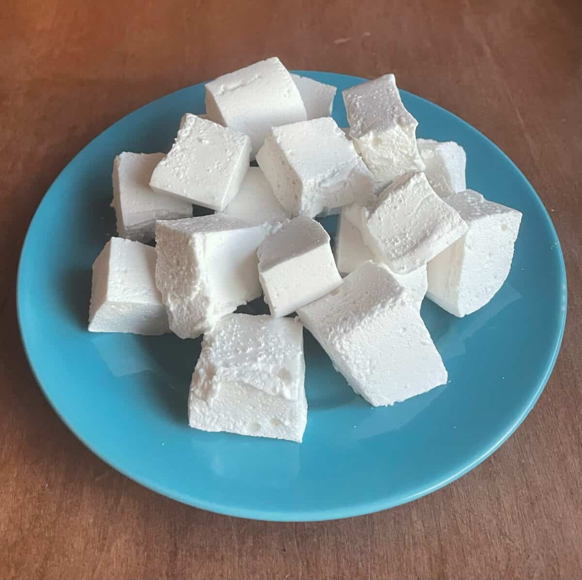 squares of homemade marshmallows on a blue plate.