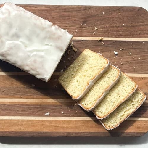 greenish lime cake with glaze cut into four slices on a cutting board.