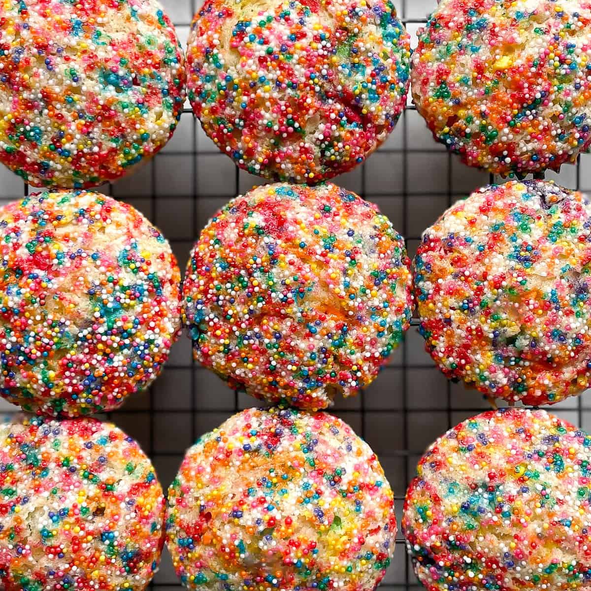 nine funfetti muffins topped with nonpareil rainbow sprinkles.